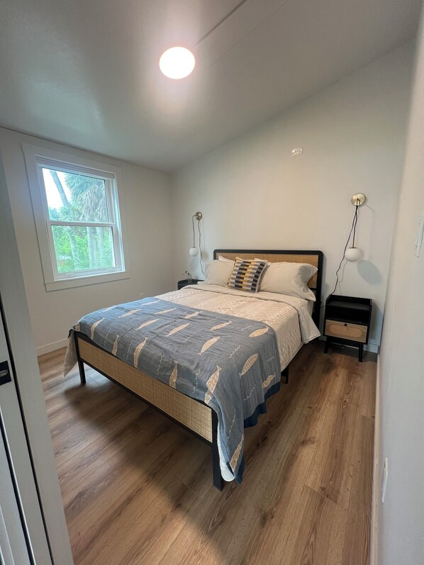 A bedroom with a bed, bedside tables, a window, and a ceiling light. - Beautiful Riverfront Escape on the Myakka – Cozy Cottage! (Venice)