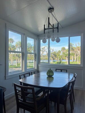 A dining area with a large table, chairs, and a ceiling light fixture. - Beautiful Riverfront Escape on the Myakka – Cozy Cottage! (Venice)