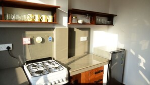 A compact kitchen with a gas stove, a refrigerator, and wooden shelves above holding kitchenware. - DADY`S Place `63`- Sunset Villa - 1 Floor - Beach in 2 Min (Hikkaduwa)