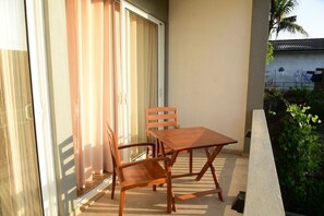 A balcony with a wooden table and chairs, a sliding glass door, and a view of a residential area with a house and greenery. - DADY`S Place `63`- Sunset Villa - 1 Floor - Beach in 2 Min (Hikkaduwa)