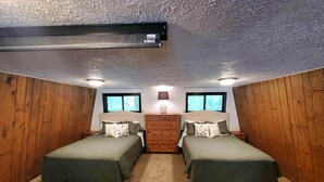 Quarto com duas camas, paredes de madeira, cômoda e janela.