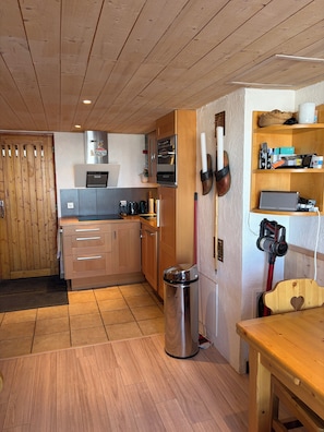 A modern kitchen with wooden cabinets, stainless steel appliances, and a wooden dining table.