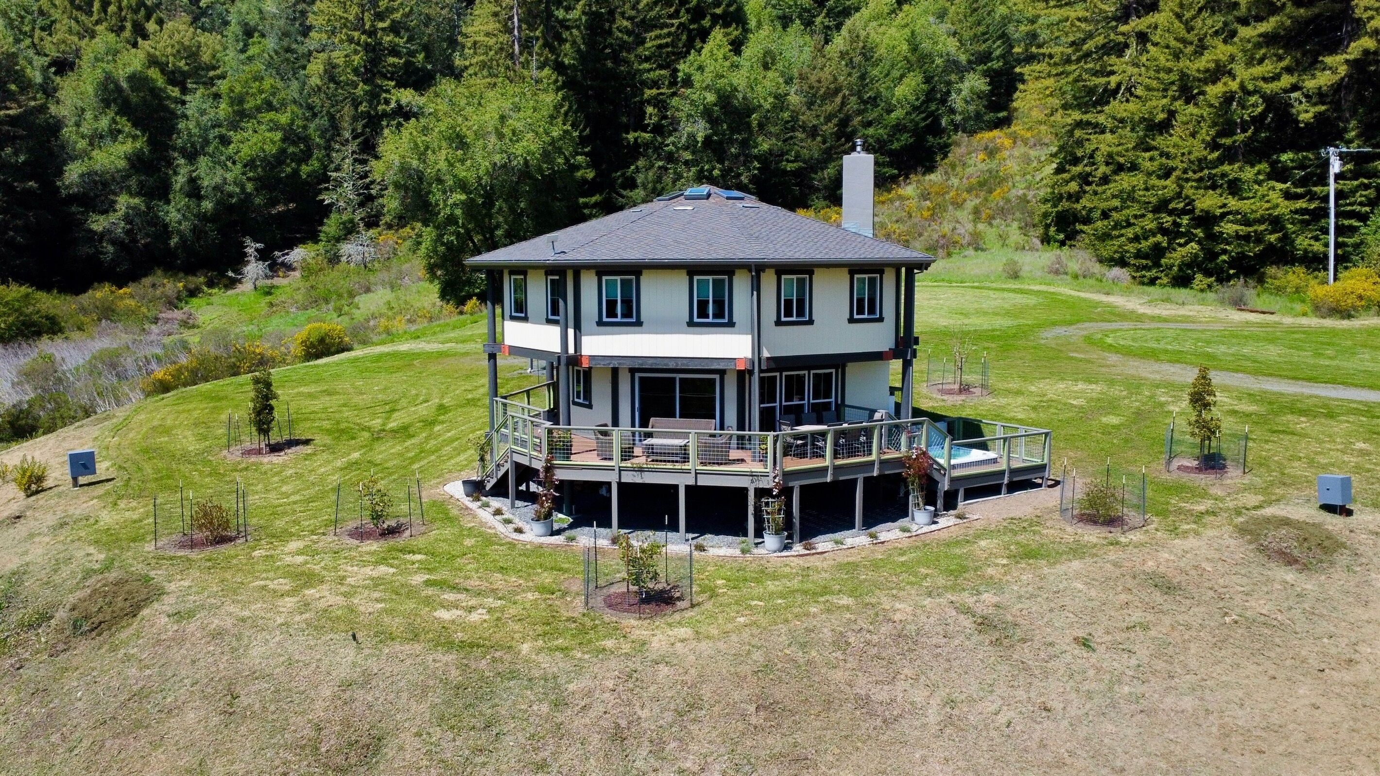 A two-story house with a balcony, surrounded by a grassy area and trees.