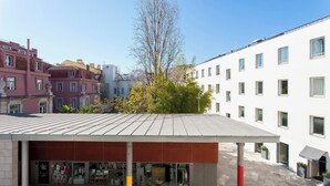 A modern building with a flat roof, a storefront with glass windows, and a red pole in the foreground. - Chiado Glamorous flat! FREE PARK! Great WI-FI!! (Lisboa)