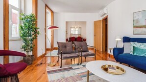 A modern living room with a sofa, armchair, and a dining area in the background. - Baixa most luminous 3 BDR flat!! Great WI-FI!!! (Lisboa)