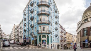 A multi-story building with balconies, a ground-level entrance, and a cobblestone street. - Baixa most luminous 3 BDR flat!! Great WI-FI!!! (Lisboa)
