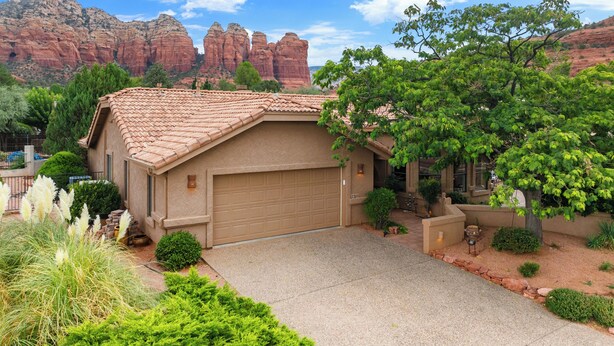 A house with a garage, surrounded by greenery and red rock formations in the background. - On the Rocks - Beautiful 3 BR / 2 bath home nestled in the heart of West Sedona (Sedona)