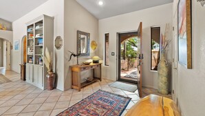 A spacious hallway with a wooden bench, a patterned rug, a console table with decorative items, and a large vase. - On the Rocks - Beautiful 3 BR / 2 bath home nestled in the heart of West Sedona (Sedona)