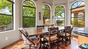 A dining area with a large wooden table, six chairs, and arched windows offering views of greenery. - On the Rocks - Beautiful 3 BR / 2 bath home nestled in the heart of West Sedona (Sedona)
