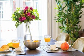 A dining table with a vase of flowers, a bowl, and plates with food and drinks. - Principe Real 2 suites upscale embracing Tejo! (Lisboa)