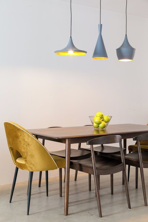 A dining area with a wooden table, four chairs, and three pendant lights. - Awarded 3 bedrooms upscale flat@Chiado/Bairro Alto (Lisboa)