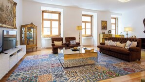 Un salón amplio con un televisor grande, dos sofás, una mesa de centro y una alfombra estampada.