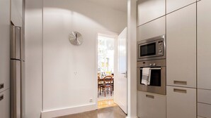 Una cocina moderna con electrodomésticos de acero inoxidable, un reloj a la vista y un comedor al fondo.