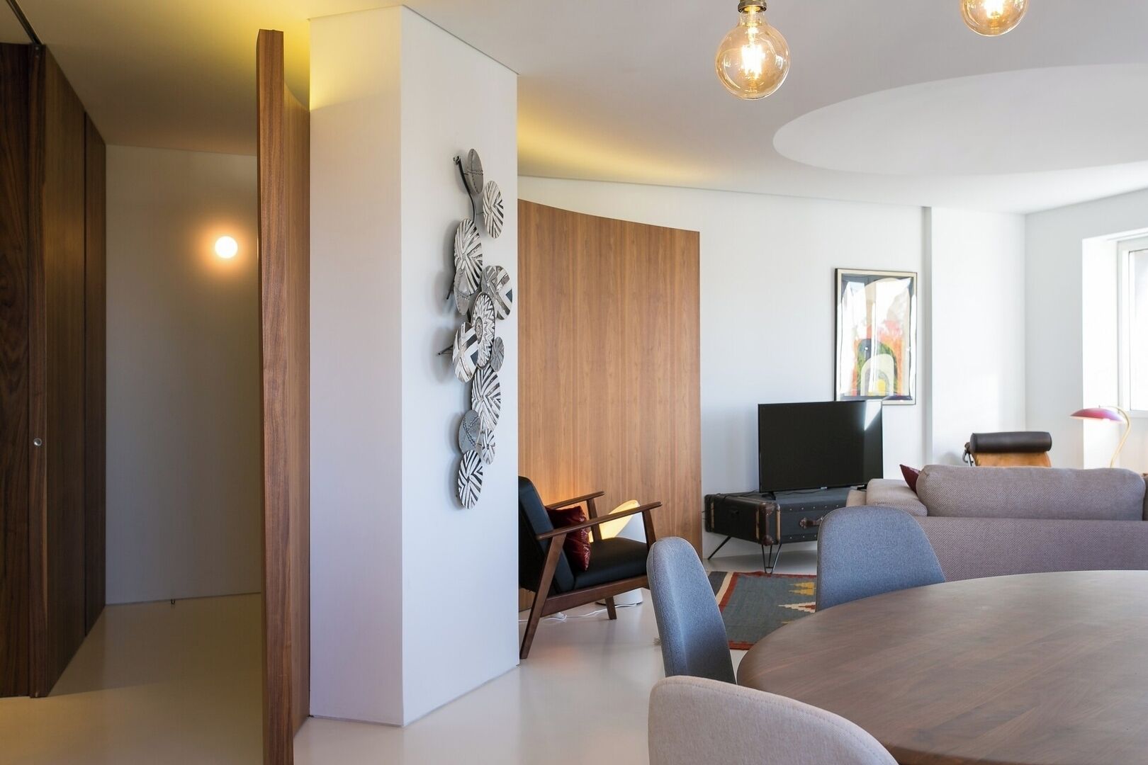 Un saló modern amb zona de menjador, televisió de pantalla plana i una gran obra d'art abstracta a la paret.