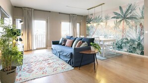 Een moderne woonkamer met een bank, een eettafel en een groot tropisch muurschildering.