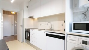 Een moderne keuken met witte kastjes, een inbouwoven, een vaatwasser en een magnetron.