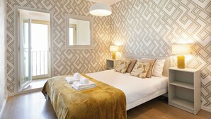 Een slaapkamer met een bed, twee bedlampjes, een spiegel en een raam.