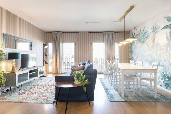 A modern living room with a sofa, TV, and dining area with chairs. - Modern 2bdr flat in the city's heart! (Lisboa)