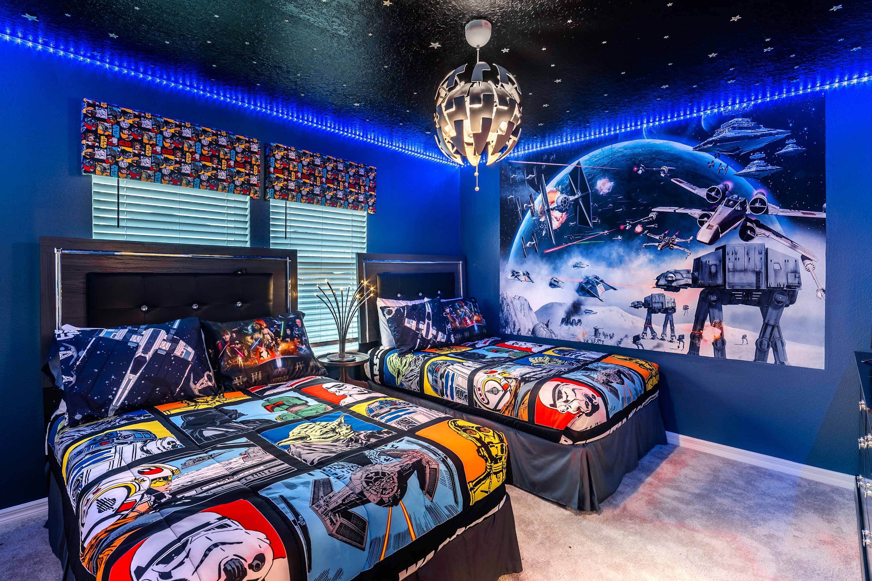Un dormitorio con dos camas, un mural grande con temática espacial y luces LED.