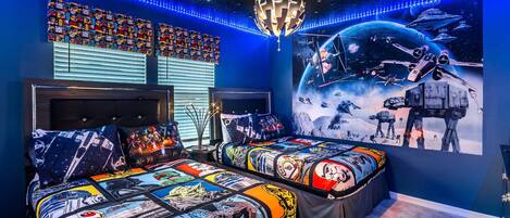Un dormitorio con dos camas, un mural grande con temática espacial y luces LED.
