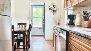 Una cucina con mobili in legno, un tavolo da pranzo con sedie, un frigorifero e una macchina da caffè.