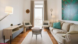 A modern living room with a sofa, two armchairs, a coffee table, and a large window with curtains.