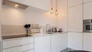 A modern kitchen with white cabinetry, a black countertop, stainless steel appliances, and pendant lighting. - Principe Real beautiful 3 bedrs flat! Great WI-FI! (Lisboa)