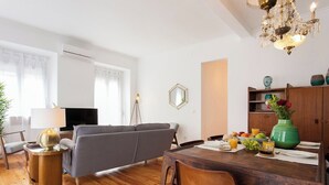 A modern living room with a grey sofa, wooden dining table, and a chandelier. - Principe Real beautiful 3 bedrs flat! Great WI-FI! (Lisboa)