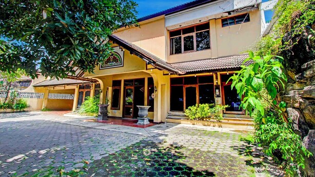 A two-story building with a tiled roof, a covered entrance, and a stone wall. - OYO 95023 Hotel Alamanda Garut (Garut)