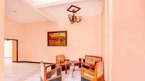 A room with a tiled floor, a chandelier, a painting on the wall, and a seating area with chairs and a table. - OYO 95023 Hotel Alamanda Garut (Garut)