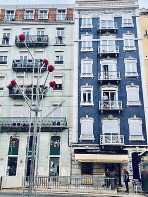 A multi-story building with balconies, a storefront, and a street lamp with red flowers. - Art Déco 4 bedrooms flat in the city center!!! (Lisboa)