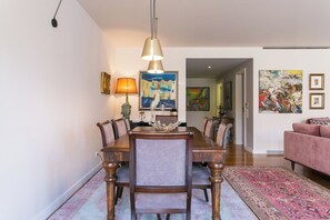 Un comedor con una mesa y sillas de madera, una lámpara colgante y obras de arte en las paredes.