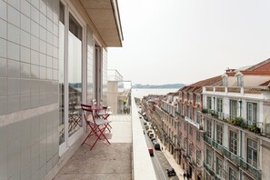 A narrow balcony with a red chair and table, overlooking a row of traditional buildings and a body of water. - Chiado 2 GLAMOUROUS Suites and PARKING! Great WI-FI! (Lisboa)