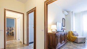Una habitación de hotel con suelo de mármol, un armario de madera, un sofá y un espejo grande.