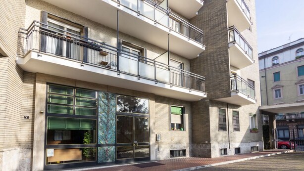 Un edificio de varios pisos con balcones, ventanas amplias y fachada de ladrillo.