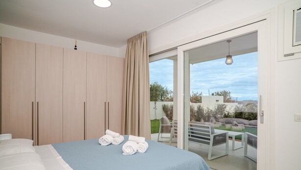 Een slaapkamer met een bed, een kledingkast en een balkon met buitenmeubilair.