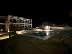 Una casa moderna con piscina por la noche.