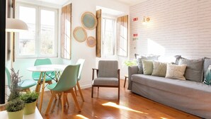 Ein modernes Wohnzimmer mit einem grauen Sofa, Türkis-Farbenen Stühlen und einem Holzessttisch.