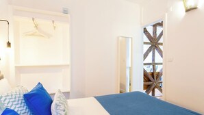Ein Schlafzimmer mit Bett, Kissen, einer Pendelleuchte, einem Kleiderschrank und einer Holzkonstruktion.