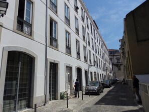 Eine schmale Straße mit weißen Häusern, großen Fenstern und einigen parkenden Autos.