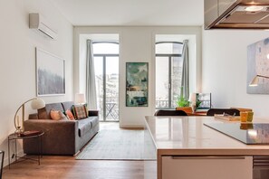Een moderne woonkamer met een bank, een salontafel en een eethoek met een keukentrap.