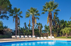 A pool area with lounge chairs and tall palm trees. - Villa Maganuco Park - Pool, Sea and Garden 300 meters from the beach (Maganuco)