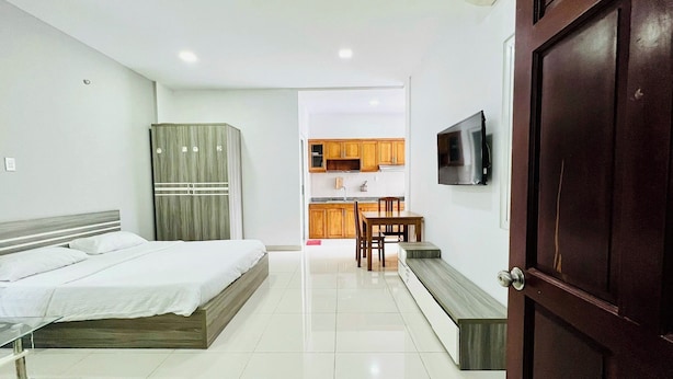 A bedroom with a bed, a wardrobe, and a TV in the adjacent room. - EMERALD APARTMENTS (Ho Chi Minh City)
