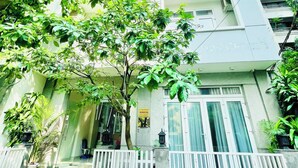 A multi-story building with a white facade, a gated entrance, and a staircase leading to the entrance. - EMERALD APARTMENTS (Ho Chi Minh City)