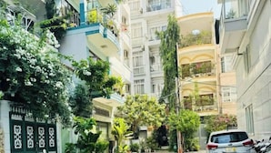 A courtyard with a row of parked motorcycles, potted plants, and a gated entrance. - EMERALD APARTMENTS (Ho Chi Minh City)