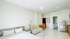 A hotel room with a bed, a sofa, a dining table, and a kitchen area. - EMERALD APARTMENTS (Ho Chi Minh City)