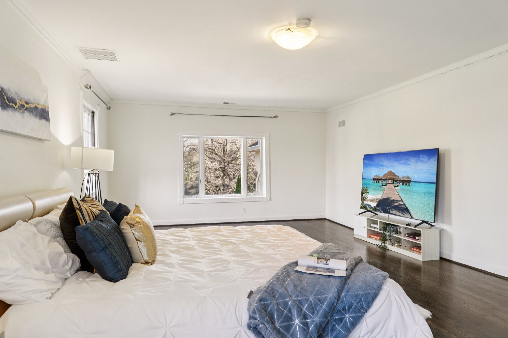 Un dormitorio amplio con una cama grande, un televisor y una ventana con vistas al exterior.