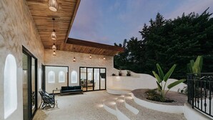 Un espace de vie extérieur moderne, doté d’un sol en pierre, de sièges et de plantes en pot.