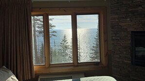 A bedroom with a large window overlooking a snowy landscape and trees. - NEWLY LISTED Lakeside 2 Queen Fireplace Studio~Pool/Hot tub/Sauna (Two Harbors)