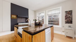 Een moderne keuken met een centraal eiland, witte kasten en een zwarte achterwand.